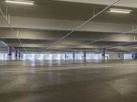 a empty parking garage, it appears to be full - sized parking lots with a yellow fire hydrant in between the two