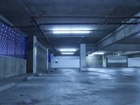 empty parking garage with blue lights in the ceiling and floor area above it is concrete
