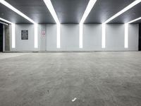 an empty office room with fluorescent lighting on the ceiling and concrete flooring in the middle