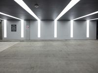 an empty office room with fluorescent lighting on the ceiling and concrete flooring in the middle