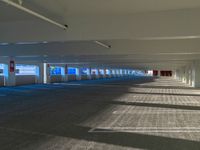 empty parking garage with light from windows and lights from doors to floor to ceiling and no cars on either side