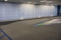 the empty garage has a painted rainbow on the concrete floor and walls that reflect from the windows