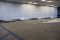 the empty garage has a painted rainbow on the concrete floor and walls that reflect from the windows