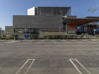 a empty parking lot with an open area below it and a building behind it in the distance