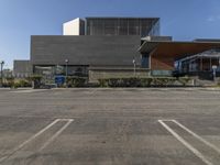 a empty parking lot with an open area below it and a building behind it in the distance