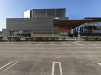 a empty parking lot with an open area below it and a building behind it in the distance