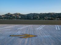 a parking lot with an arrow painted on the surface of it and signs in the background