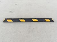 a long black and yellow barrier strip sitting on the ground in the parking lot at an airport