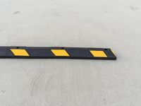 a long black and yellow barrier strip sitting on the ground in the parking lot at an airport