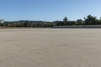 a young boy is flying a skateboard on the concrete lot under blue sky in the town