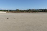 a young boy is flying a skateboard on the concrete lot under blue sky in the town