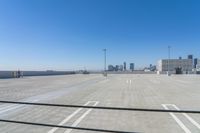 there is an empty parking lot next to the tall buildings in the background, on a sunny day