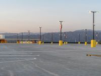 there are several large poles in a parking lot with mountains in the background in the foreground