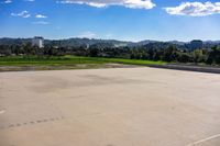 a empty concrete parking lot with the sun in the background and trees in the distance