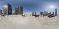 an empty parking lot with cars and tall buildings in the background at a city intersection