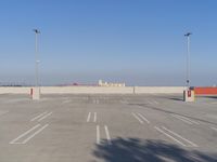 a large parking lot with tall lamp posts and white lines in it in the middle of the image