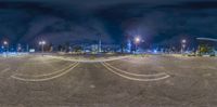 a parking lot with lights on and some signs on it at night time as seen from a fish eye