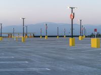 a parking lot filled with lots of parking lamps and poles near a mountain range in the background