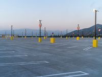 a parking lot filled with lots of parking lamps and poles near a mountain range in the background