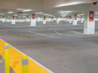 an empty parking garage filled with yellow barriers and yellow signs below the doors of them