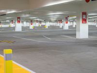an empty parking garage filled with yellow barriers and yellow signs below the doors of them