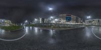 a large empty parking lot with a big building in the distance at night with no lights on