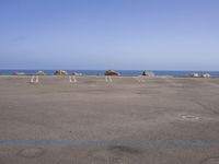 an empty parking lot near the water with rocky shoreline in the background during the day