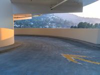 parking lot with yellow markings and mountains in the background by a large open parking garage