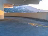 parking lot with yellow markings and mountains in the background by a large open parking garage