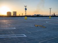 a parking lot with no parking signs on it near a tall city skyline at sunset