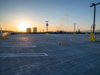 a parking lot with no parking signs on it near a tall city skyline at sunset