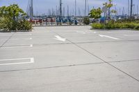 a large parking lot with two white arrows painted in it, next to other boats