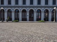 the road outside is a small plaza with two pillars and four archways and an old building with windows