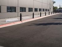 a street in front of a building has black poles with red line in front of the corner