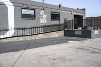 a gray brick building with black fences on both sides and graffiti on the side of it