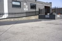 a gray brick building with black fences on both sides and graffiti on the side of it