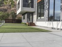 concrete pavers installed to a modern house with grass and glass walls on a concrete patio area