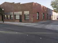 the bricked building with black doors is on the corner of a street in front of some trees