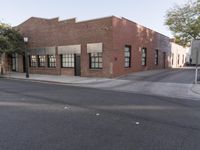 the bricked building with black doors is on the corner of a street in front of some trees