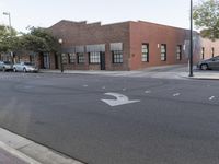 the bricked building with black doors is on the corner of a street in front of some trees