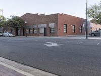 the bricked building with black doors is on the corner of a street in front of some trees