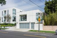 the street view shows a two level, white residential building with multiple garages and attached parking spots