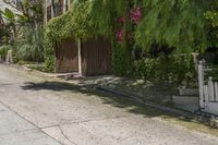 a person walking down the street past an gate, and a house in the background