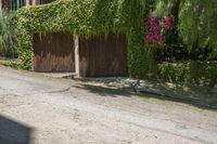 a person walking down the street past an gate, and a house in the background