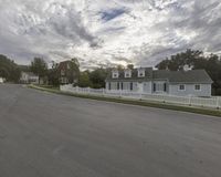 a small home sits along the side of the road near a town street with homes in the background