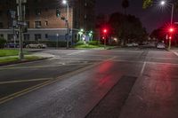 two red stop lights on a city street at night time and the street is wet