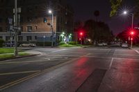 two red stop lights on a city street at night time and the street is wet