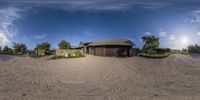 a house is shown with sand and sky in the background for a fish eye view