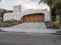 this driveway features a curved garage and decorative landscaping, which leads into the house's outdoor space