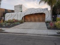 this driveway features a curved garage and decorative landscaping, which leads into the house's outdoor space